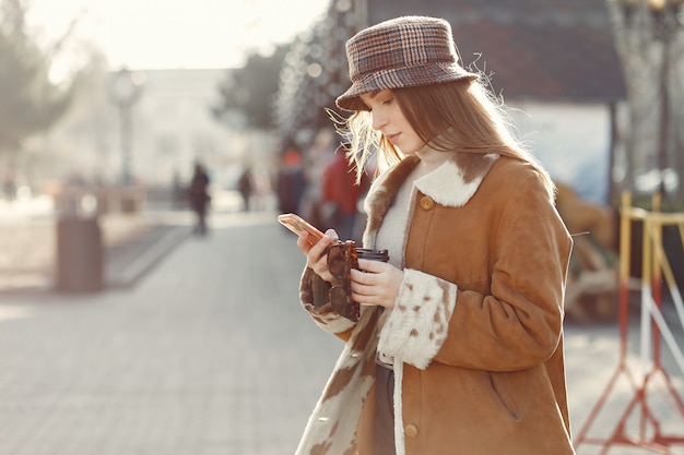 Mädchen, das in einer Frühlingsstadt geht und ein Telefon benutzt