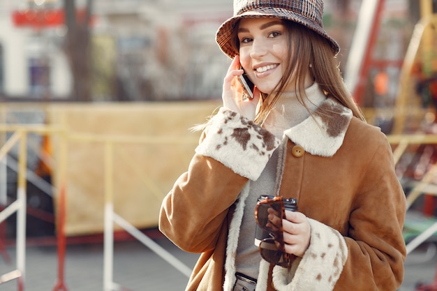 Mädchen, das in einer Frühlingsstadt geht und ein Telefon benutzt