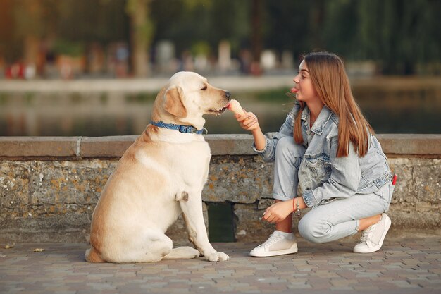 Mädchen, das in einer Frühlingsstadt mit niedlichem Hund geht