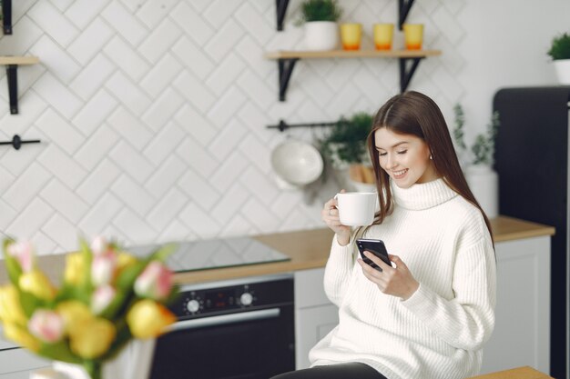 Mädchen, das in einer Küche sitzt und einen Kaffee trinkt