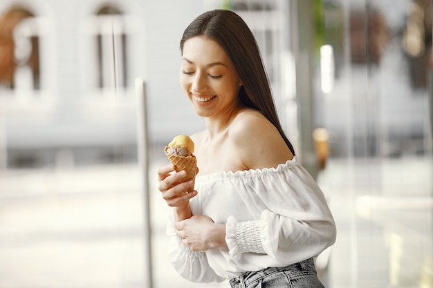 Mädchen, das in einer Sommerstadt mit Eiscreme steht