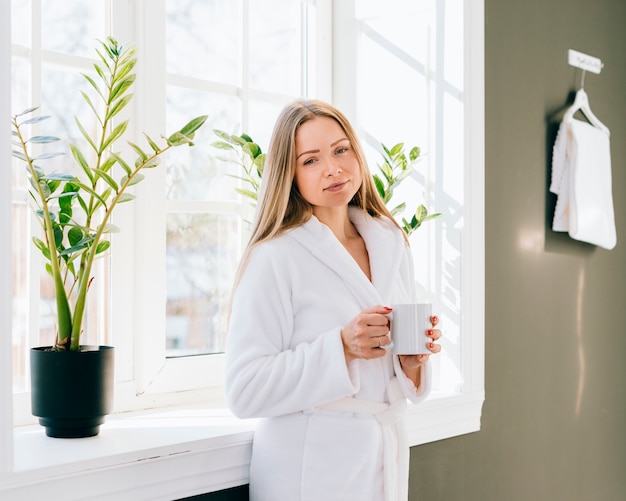 Kostenloses Foto mädchen, das kaffee am badezimmer trinkt