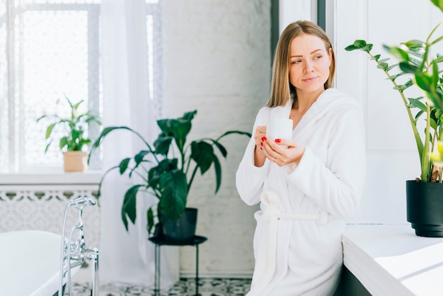 Mädchen, das Kaffee am Badezimmer trinkt