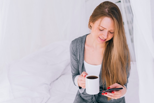 Mädchen, das Kaffee mit dem Handy trinkt