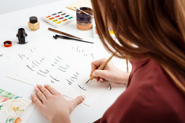 Mädchen, das Kalligraphie auf Postkarten schreibt. Kunstdesign.
