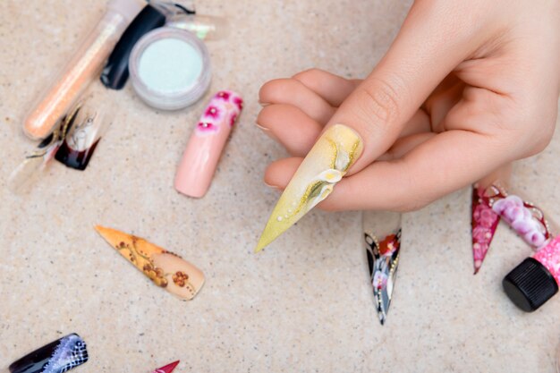 Mädchen, das künstliche Nagelspitzen mit Blumennageldesign versucht