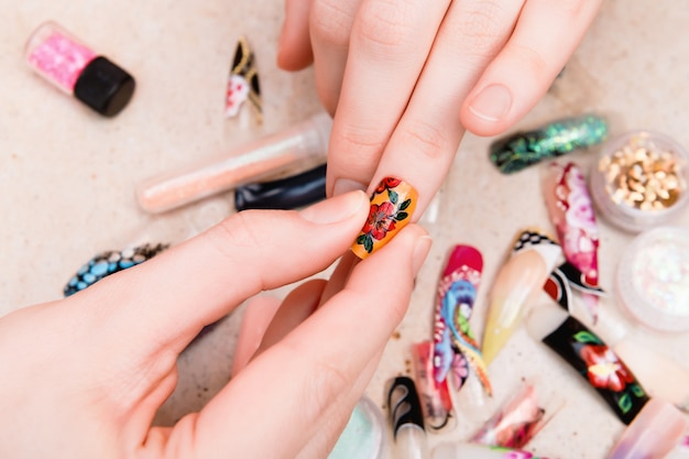 Mädchen, das künstliche Nagelspitzen mit Blumennageldesign versucht