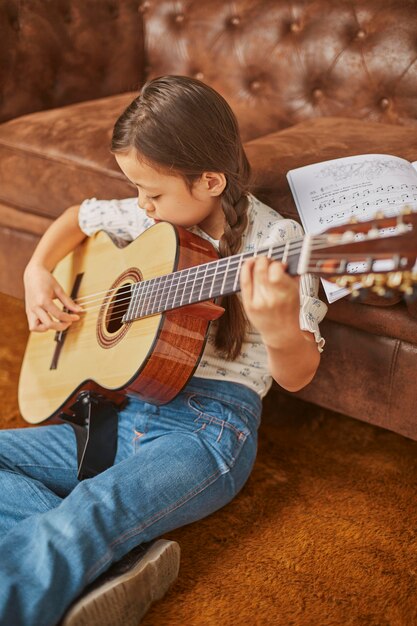 Mädchen, das lernt, wie man zu Hause Gitarre spielt