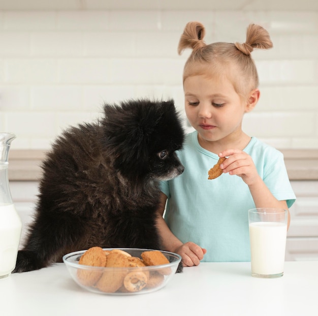 Mädchen, das Milch trinkt und mit Hund spielt