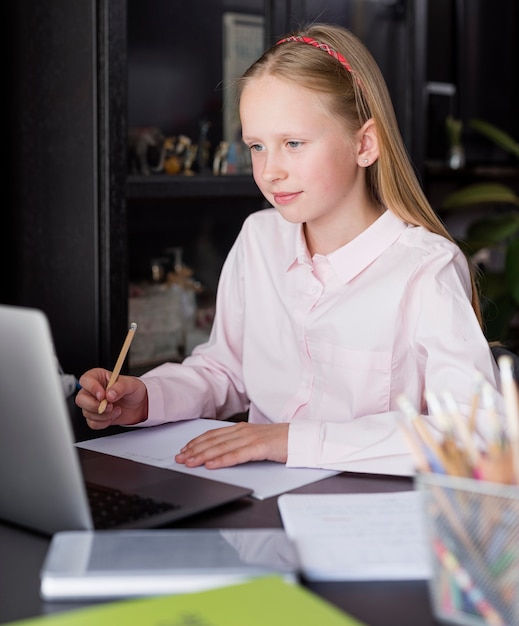 Mädchen, das Notizen in der Online-Klasse macht