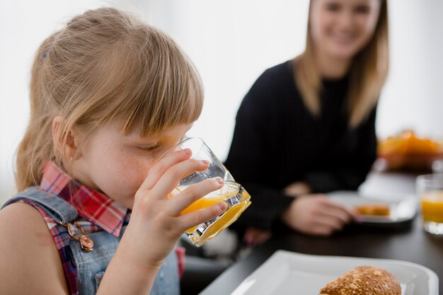 Mädchen, das Saft nahe Mutter genießt