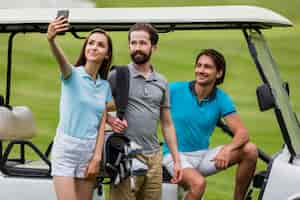 Kostenloses Foto mädchen, das selfie mit freunden auf golffeld nimmt