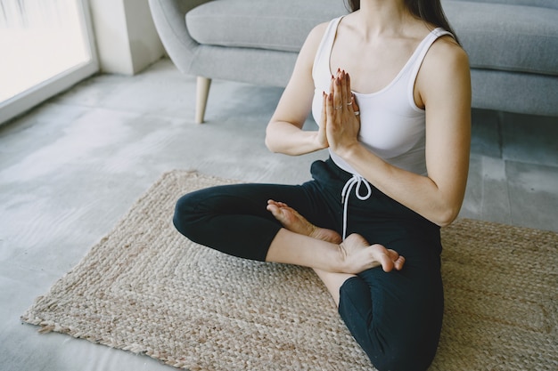 Mädchen, das Yoga-Übungen zu Hause nahe Sofa und Fenster in Sportbekleidung tut