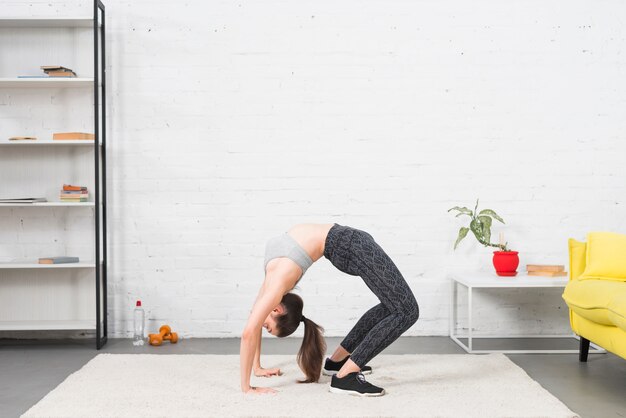 Mädchen, das Yoga in ihrem Haus bildet