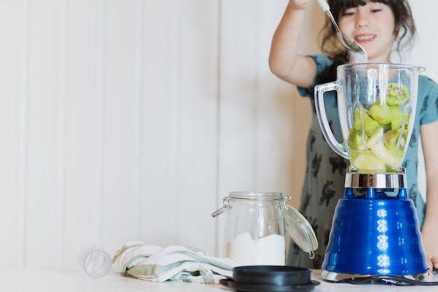 Kostenloses Foto mädchen, das zucker zur mischmaschine setzt