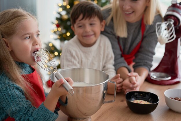 Mädchen, das Zuckerpaste während des Backens mit Familie schmeckt