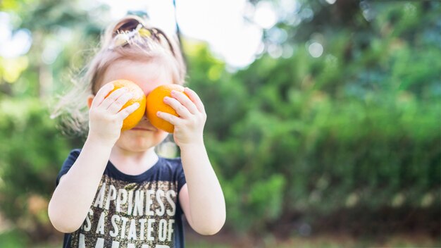 Mädchen, das zwei Orangen über ihren Augen hält