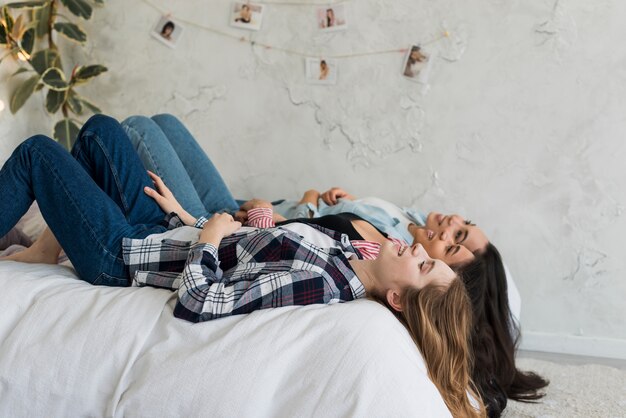 Mädchen, die auf dem Bett mit den Beinen auf den Rückseiten und den Haaren liegen, die hinuntergehen