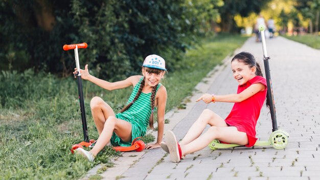 Mädchen, die auf ihrem Stoßroller macht Spaß im Park sitzen