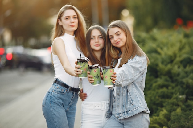 Mädchen, die in einer Frühlingsstadt gehen und Kaffee nehmen