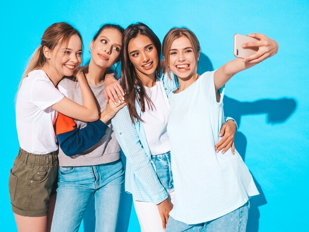 Mädchen, die selfie Selbstporträtfotos auf Smartphone machen Modelle, die nahe blauer Wand im Studio, Frau zeigt positive Gesichtsgefühle aufwerfen
