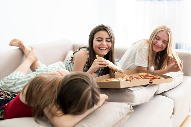 Mädchen, die sich nach Hause entspannen und Pizza essen