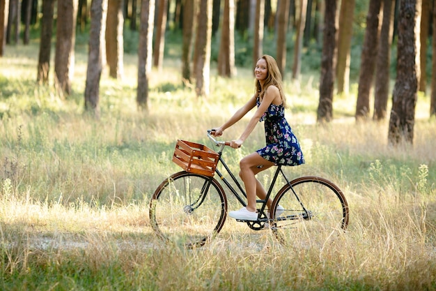 Mädchen fährt Fahrrad mit einem Korb im Wald.