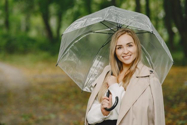 Mädchen geht. Frau in einem braunen Mantel. Blond mit Regenschirm.