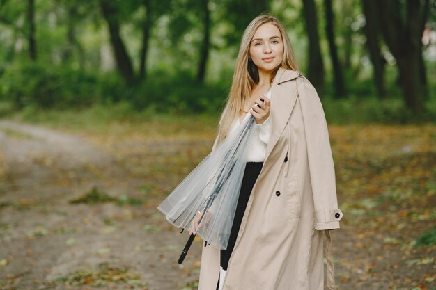 Mädchen geht. Frau in einem braunen Mantel. Blond mit Regenschirm.