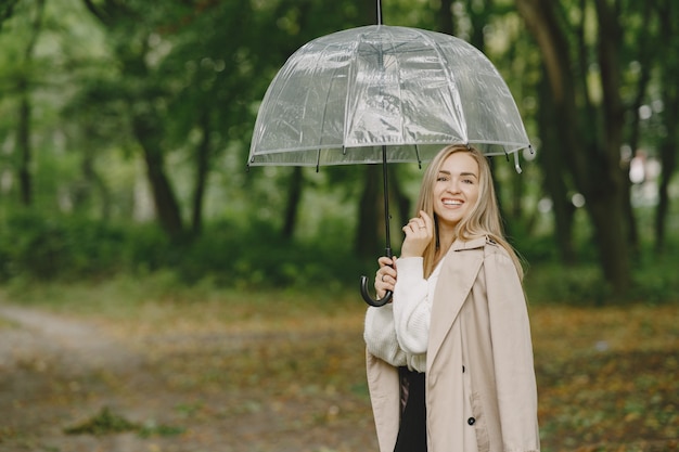 Kostenloses Foto mädchen geht. frau in einem braunen mantel. blond mit regenschirm.