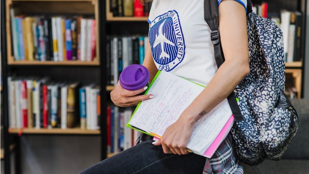 Mädchen hält Arbeitsbuch mit Rucksack