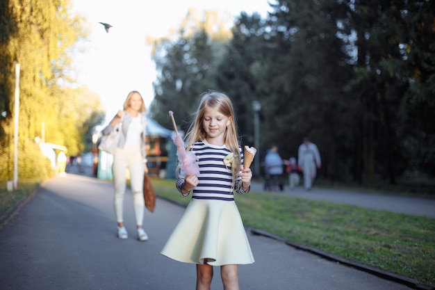 Mädchen hält einen Stock mit Zuckerwolke und ein Eis