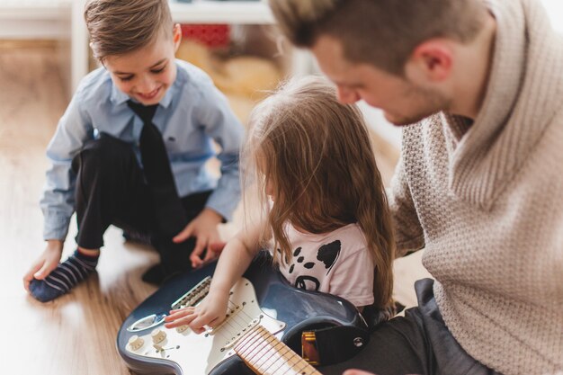 Mädchen hat Spaß mit der Gitarre ihres Vaters