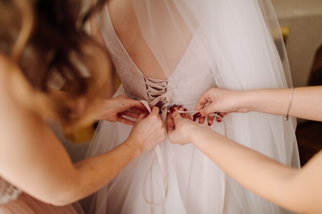 Mädchen helfen Braut, ihr Kleid anzuziehen