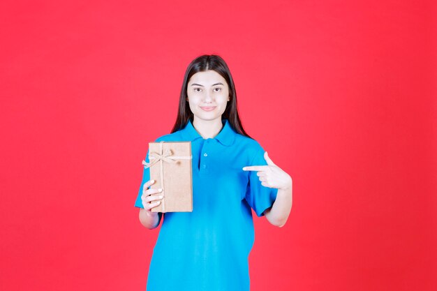 Mädchen im blauen Hemd mit einer Mini-Geschenkbox aus Pappe