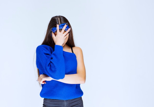 Mädchen im blauen Partykleid, das den Kopf hält, während sie verwirrt und überrascht ist.