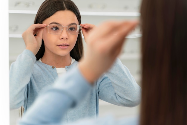 Mädchen im Brillengeschäft, das an den Gläsern versucht