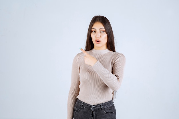 Mädchen im grauen Pullover zeigt etwas auf der linken Seite.