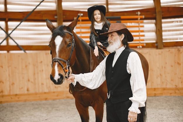 Mädchen im Helm, das Reiten lernt. Der Lehrer unterrichtet ein kleines Mädchen.