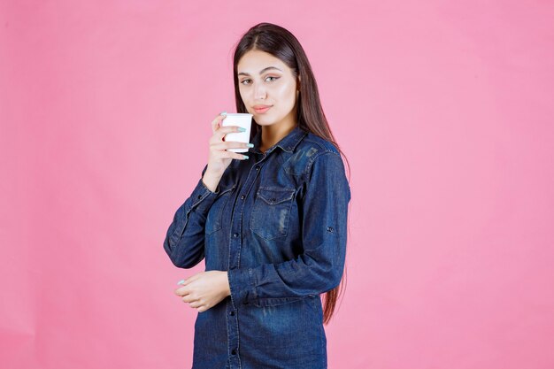 Mädchen im Jeanshemd, das eine Tasse Kaffee trinkt