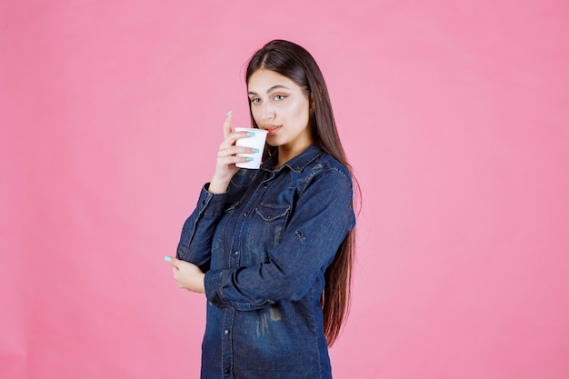 Mädchen im Jeanshemd, das eine Tasse Kaffee trinkt