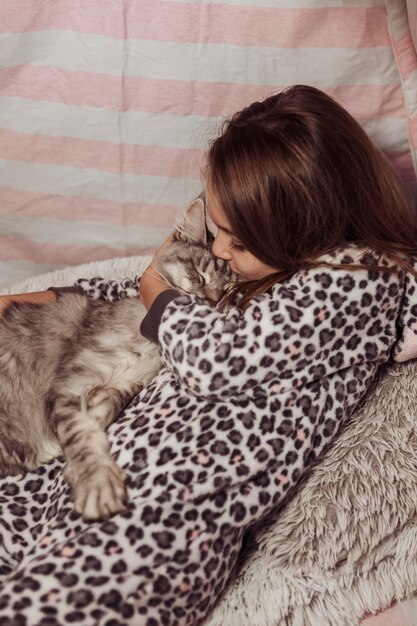 Mädchen im Pyjama küsst ihre Katze