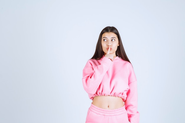 Kostenloses Foto mädchen im rosa pyjama, das um stille bittet