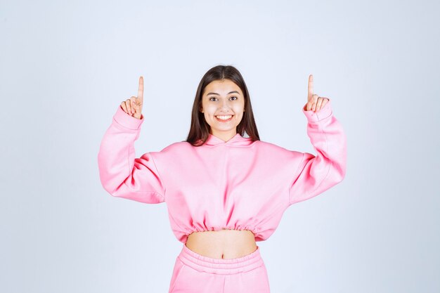 Mädchen im rosa Pyjama, der nach oben mit emotionalem Gesicht zeigt