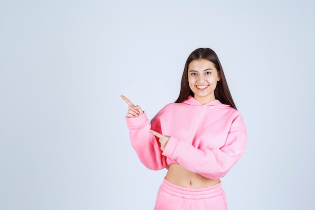 Mädchen im rosa Pyjama zeigt auf die linke Seite