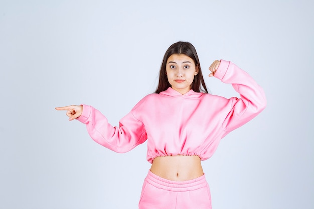 Mädchen im rosa pyjama zeigt auf etwas auf der linken seite