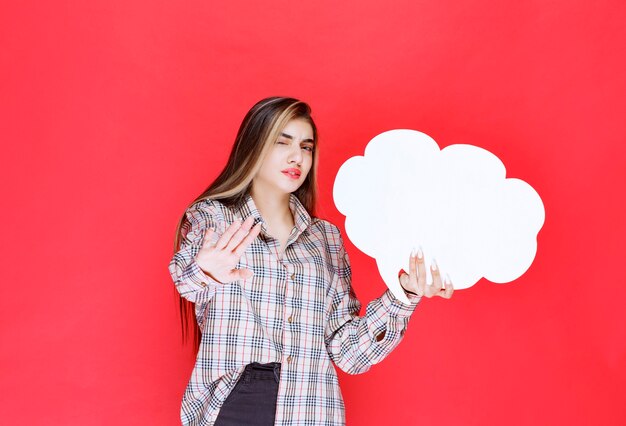 Mädchen im warmen Pullover, der ein Ideenboard in Wolkenform hält und sich weigert, es zu spielen