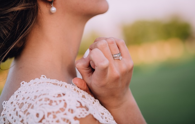 Kostenloses Foto mädchen im weißen kleid und mit den weißen ohrringen, die hände nahe hals halten