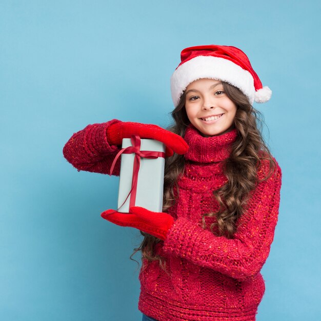 Mädchen im Winter kleidet mit einem Geschenk in ihren Händen