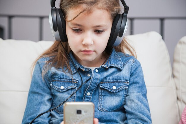 Mädchen in den Kopfhörern, die Smartphone verwenden